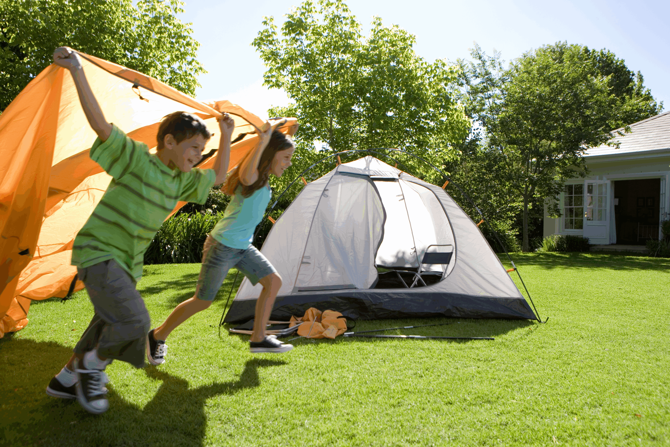 Two kids running in front of a tent set up in the backyard for this fun summer activity. 