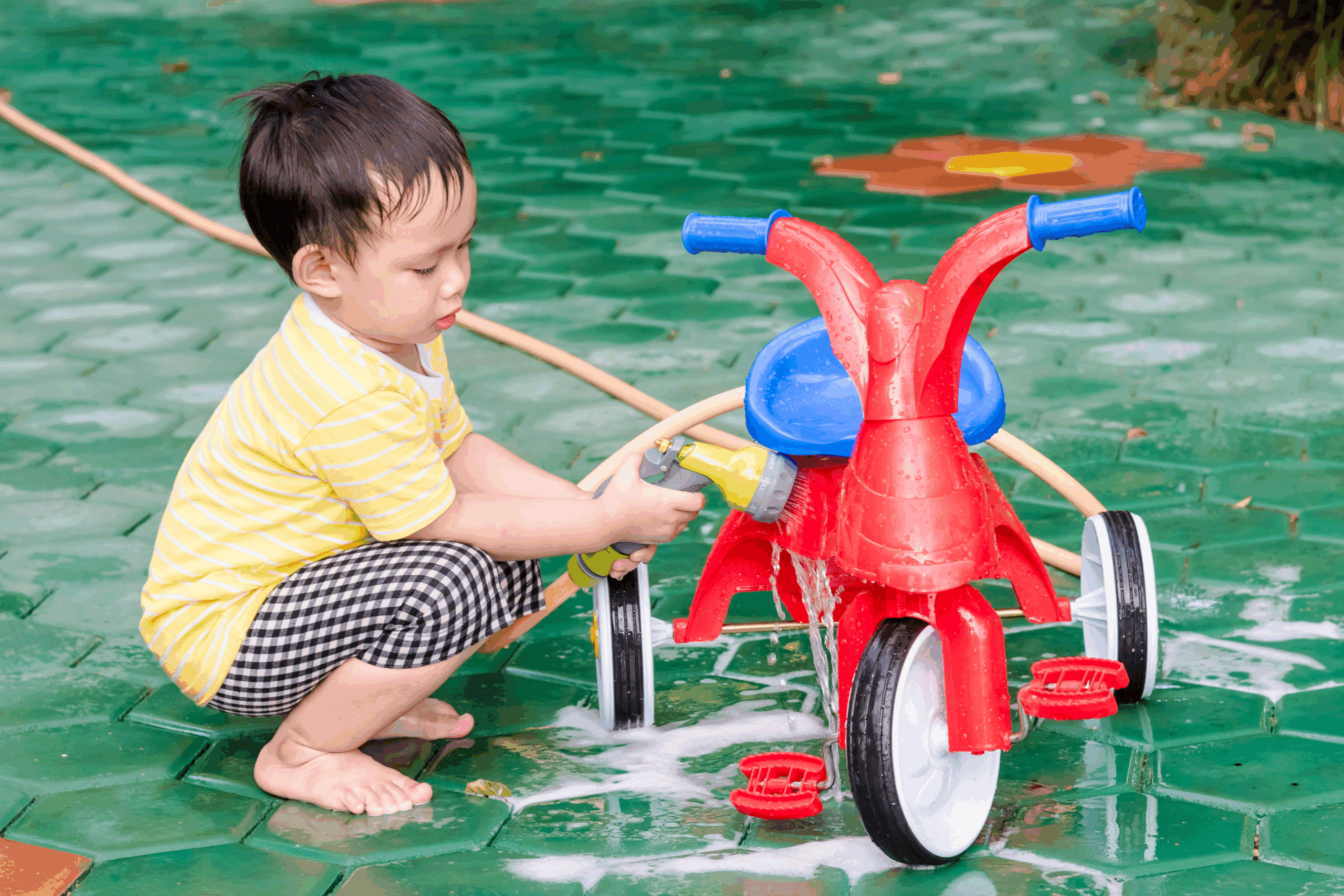A young boy washing his bike in the summer time. 