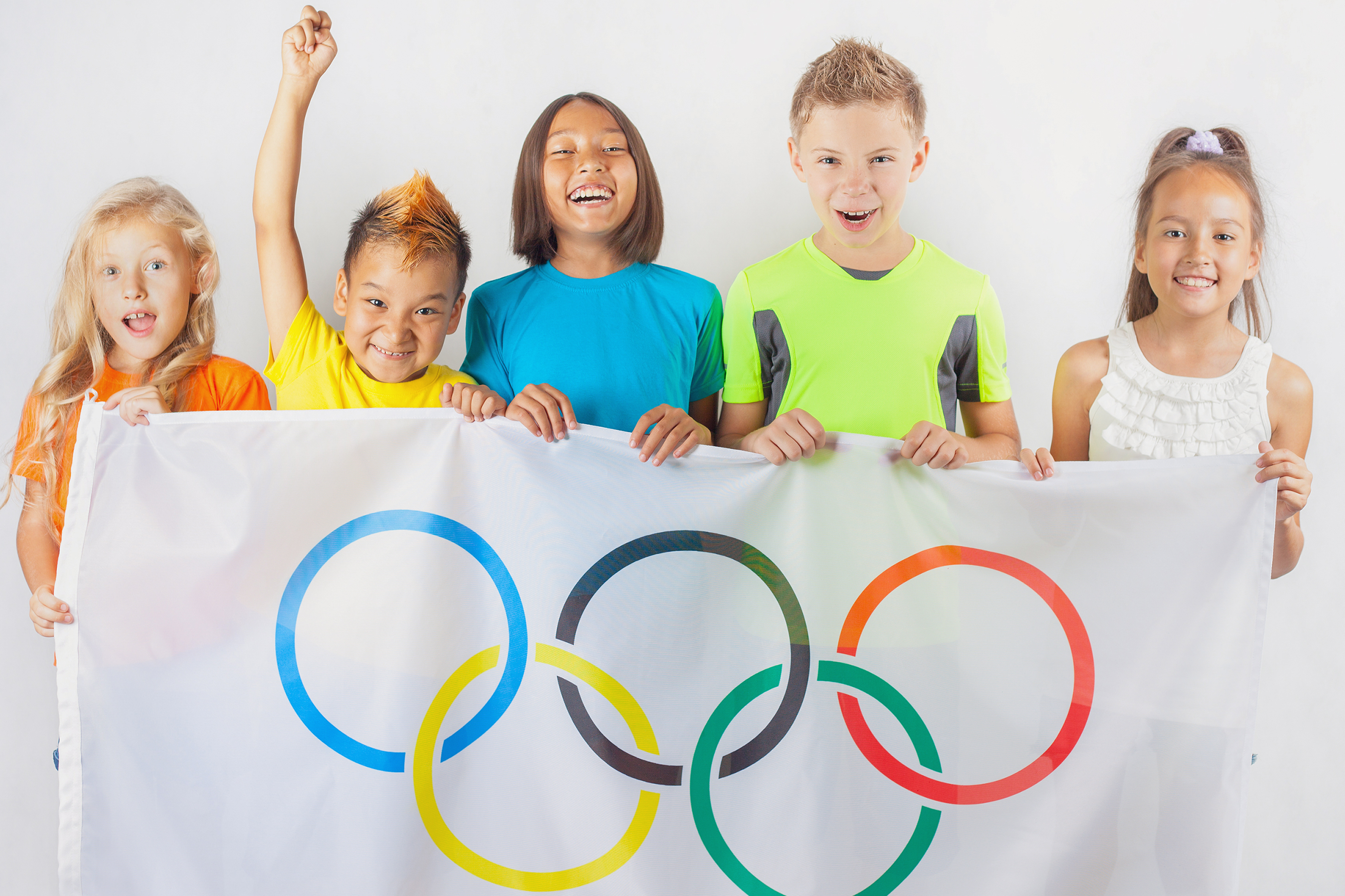 A group of young kids holding an Olympic sign banner. 