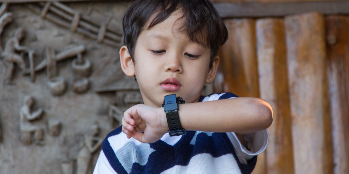 A young boy looking at his watch to try and tell what time it is. 