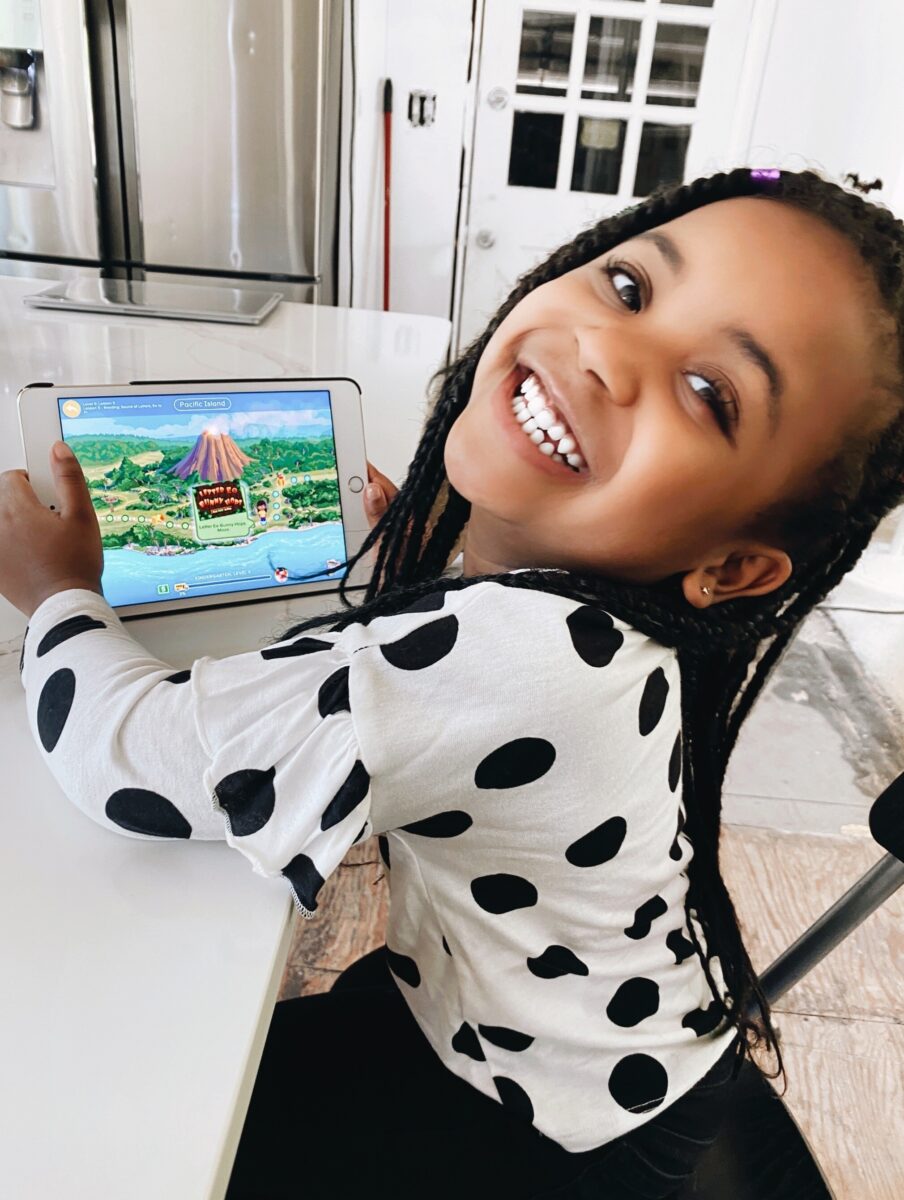 A young girl smiling while playing ABCmouse on the I-pad. 