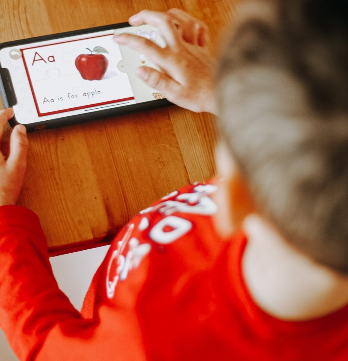 Young boy playing a reading game on an i-pad.