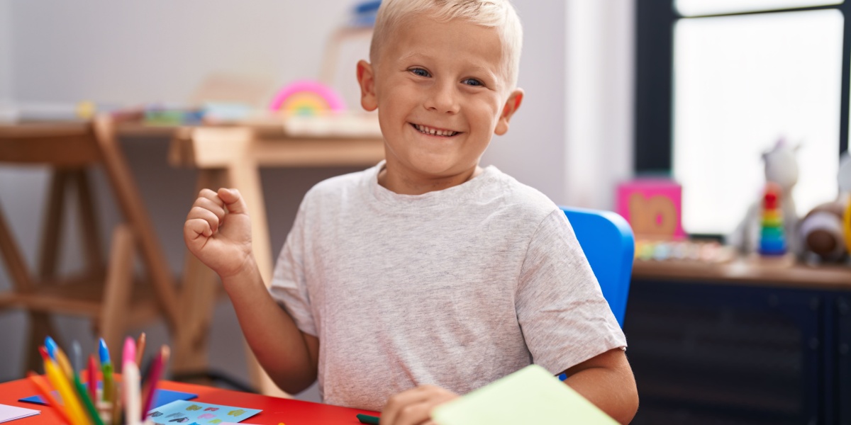 A young boy working on a project with a big grin on his face. 
