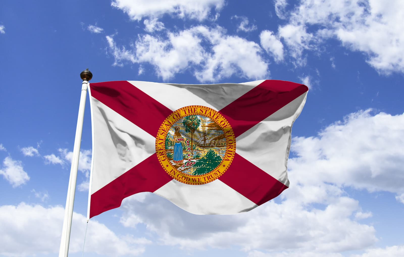 State flag of Florida blowing in the wind with a blue sky and clouds background.