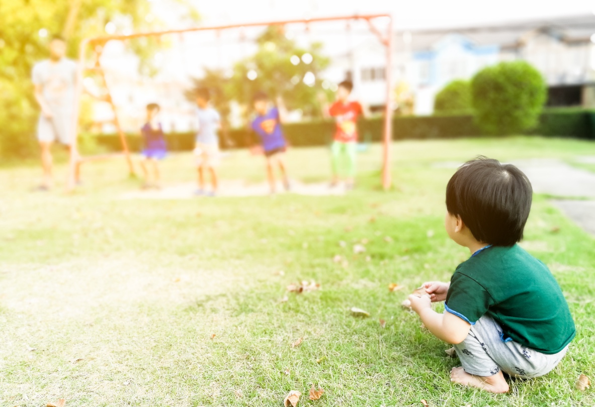 A child watching other children playing on a swing set in an example of onlooker play. 
