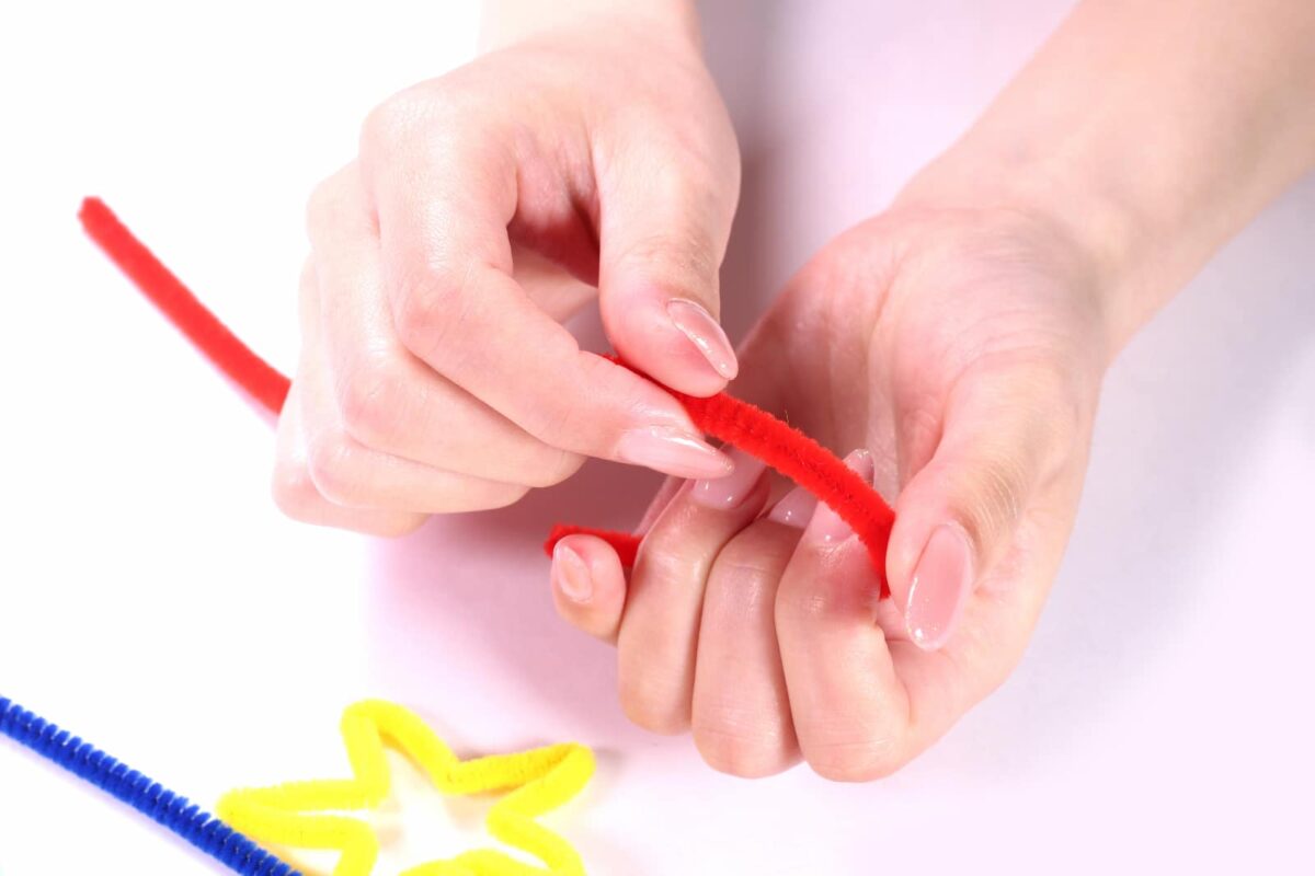 Hands creating colorful pipe cleaner shapes. 