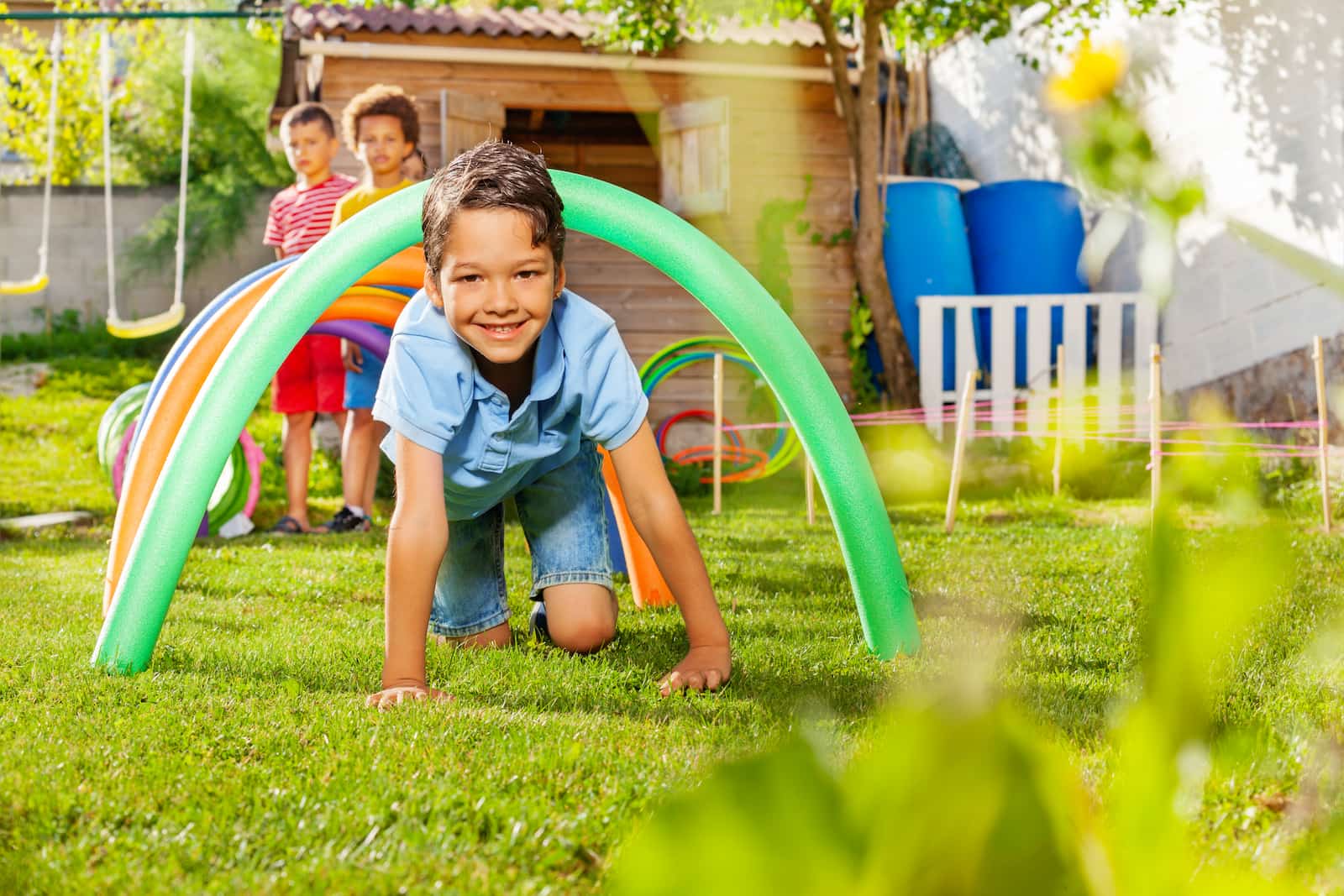 A young boy playing outside with friends in a fun DIY obstacle course. 