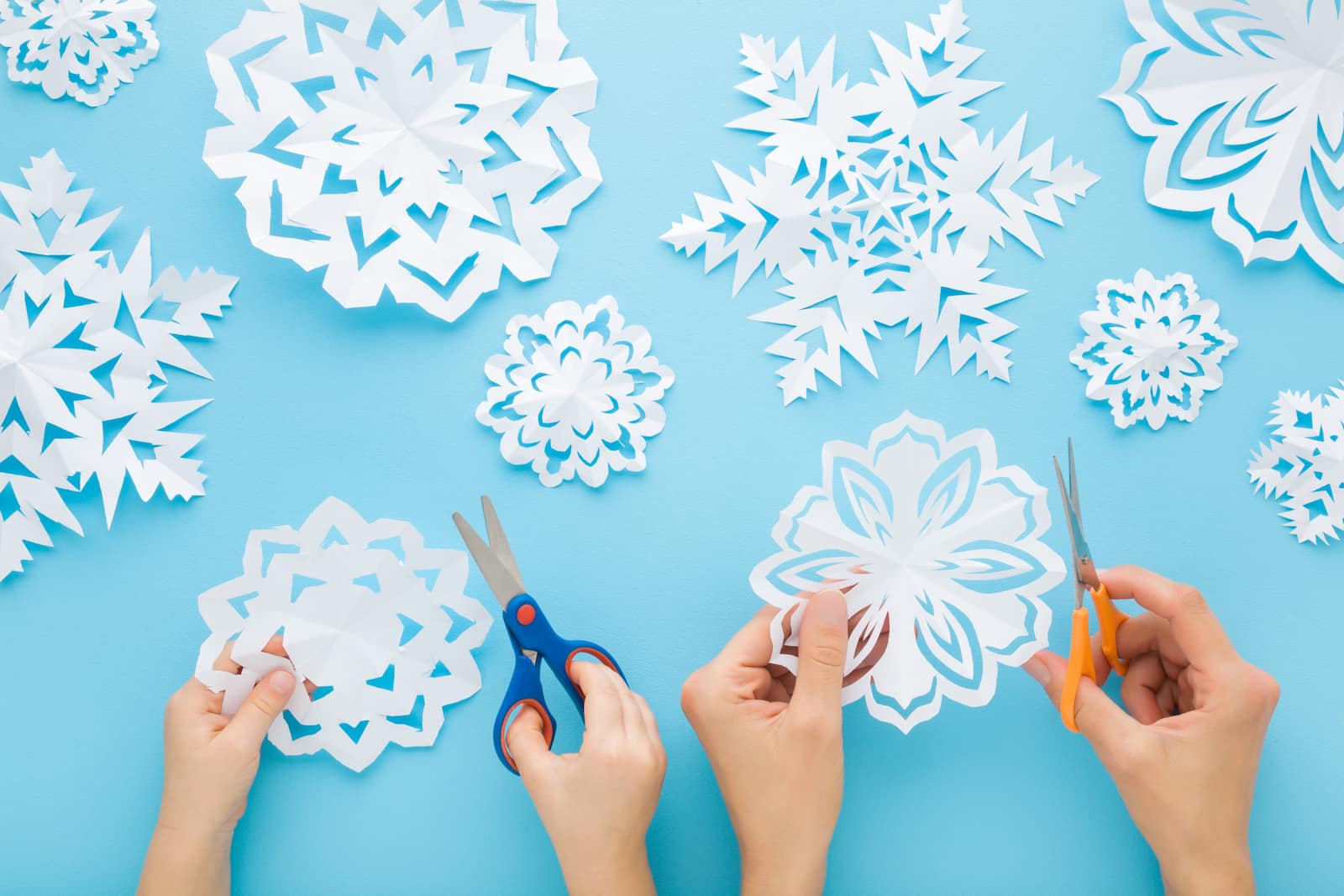 Beautiful paper snowflakes cut from white paper and laid on a light blue background. 
