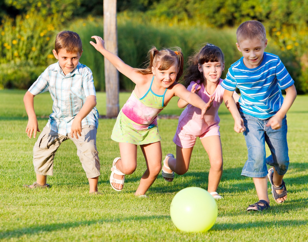 Children playing in a field kicking a ball together. 