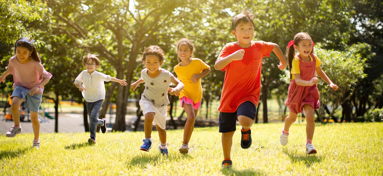 Children running across a field together playing outdoors.  