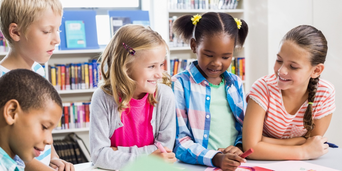 Children working together in a school library doing a craft together. 