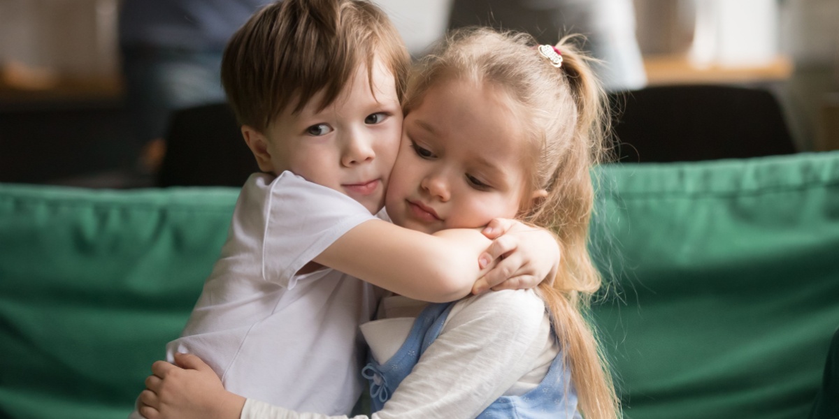 Two young children hugging each other.