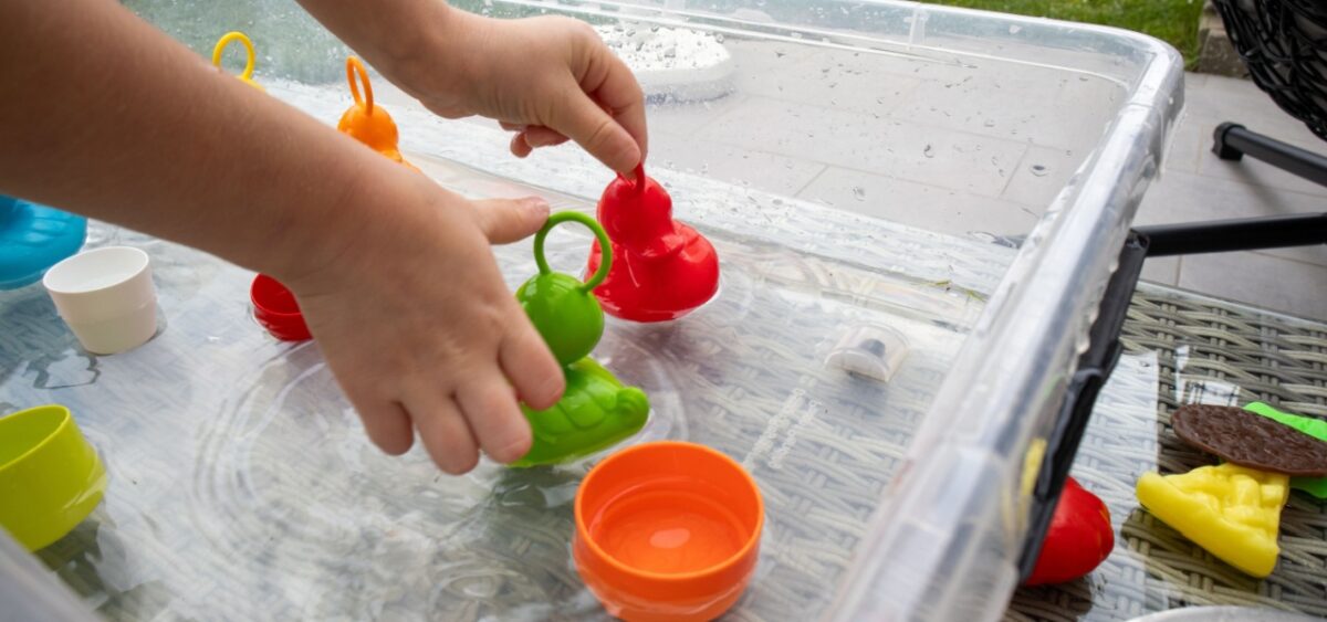 A sensory water bin with small toys for children to play in. 