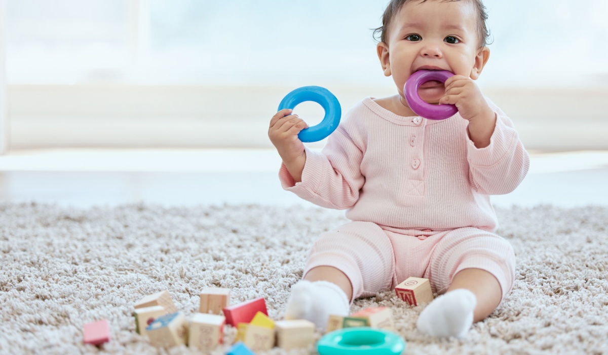 A baby putting a colorful toy ring in her mouth. 
