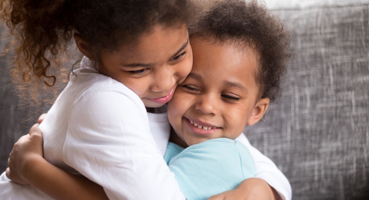 Two young children hugging each other. 
