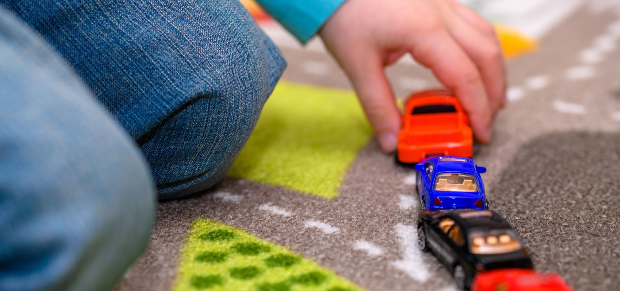 A child lining toy cars up in a pattern. 