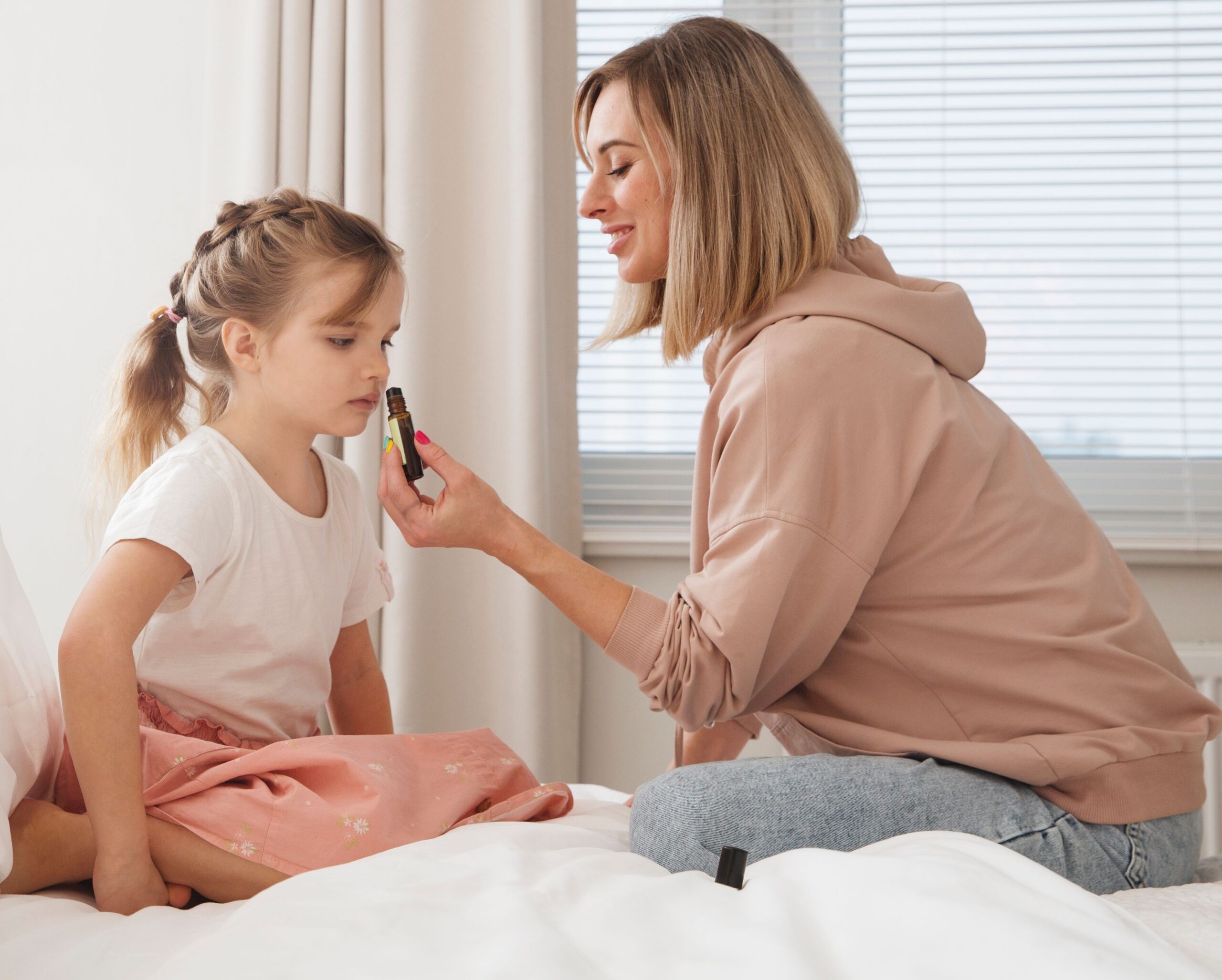 A mother holding a bottle of essential oil to the nose of her daughter for a sensory experience. 