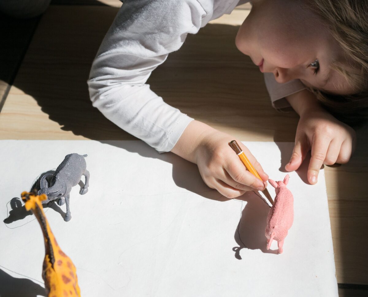 A child tracing the shadows of plastic animals in this sensory activity for kids. 