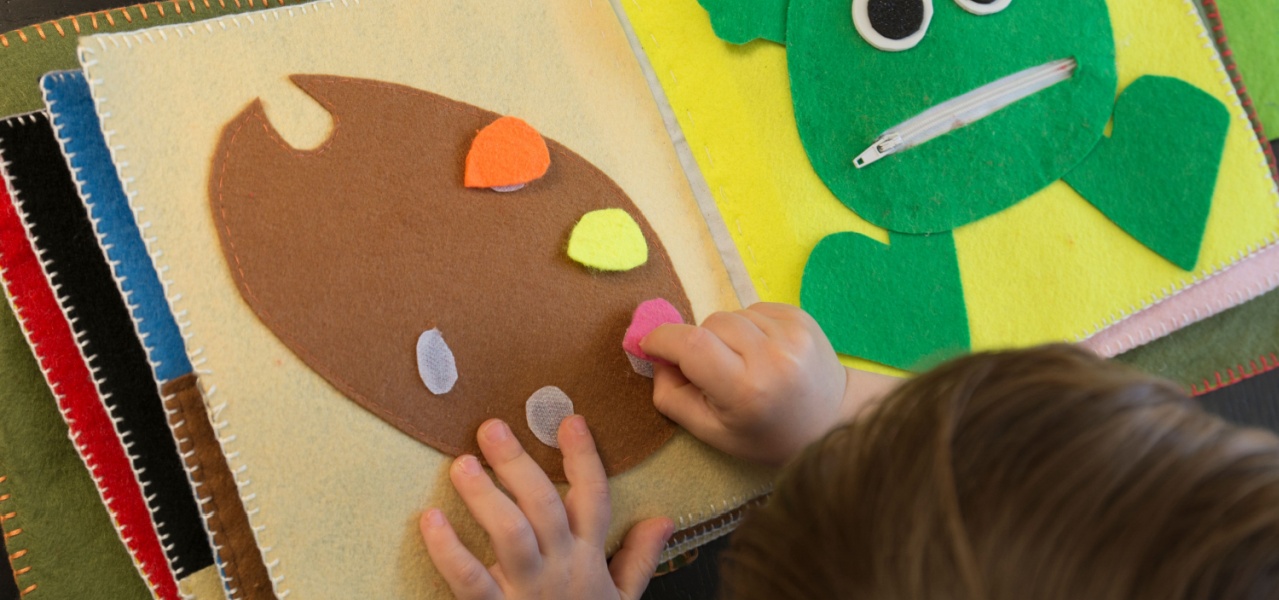 A child playing with fabric sensory book. 
