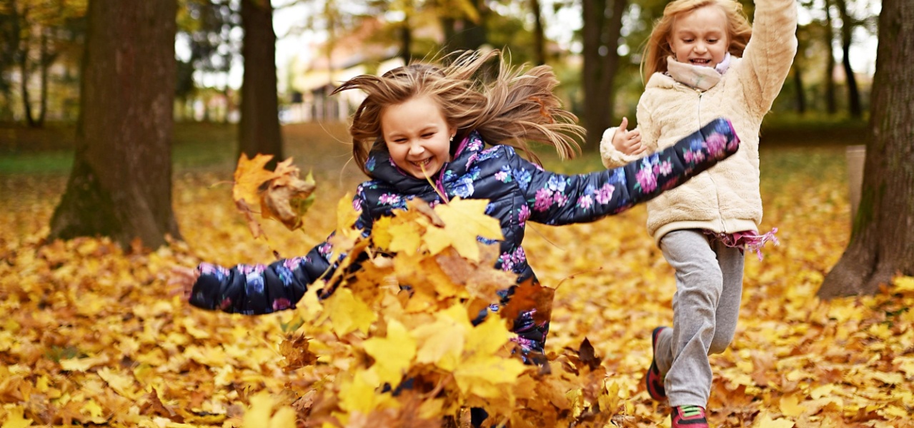 Children playing in a pile of leaves for this fun fall sensory game.
