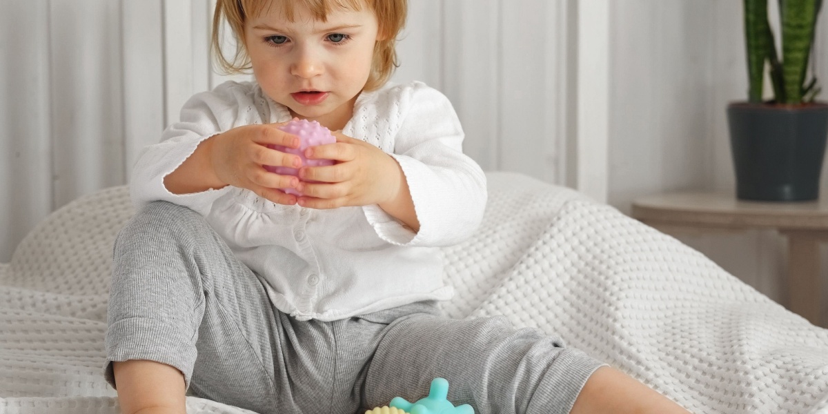 A young girl playing with a textured ball during sensory play. 