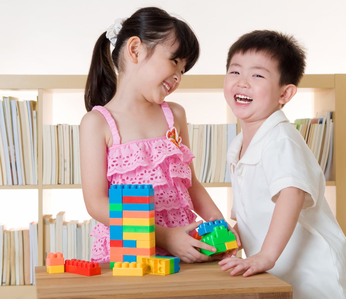Two young children playing with blocks  at a table engaging in cooperative play. 
