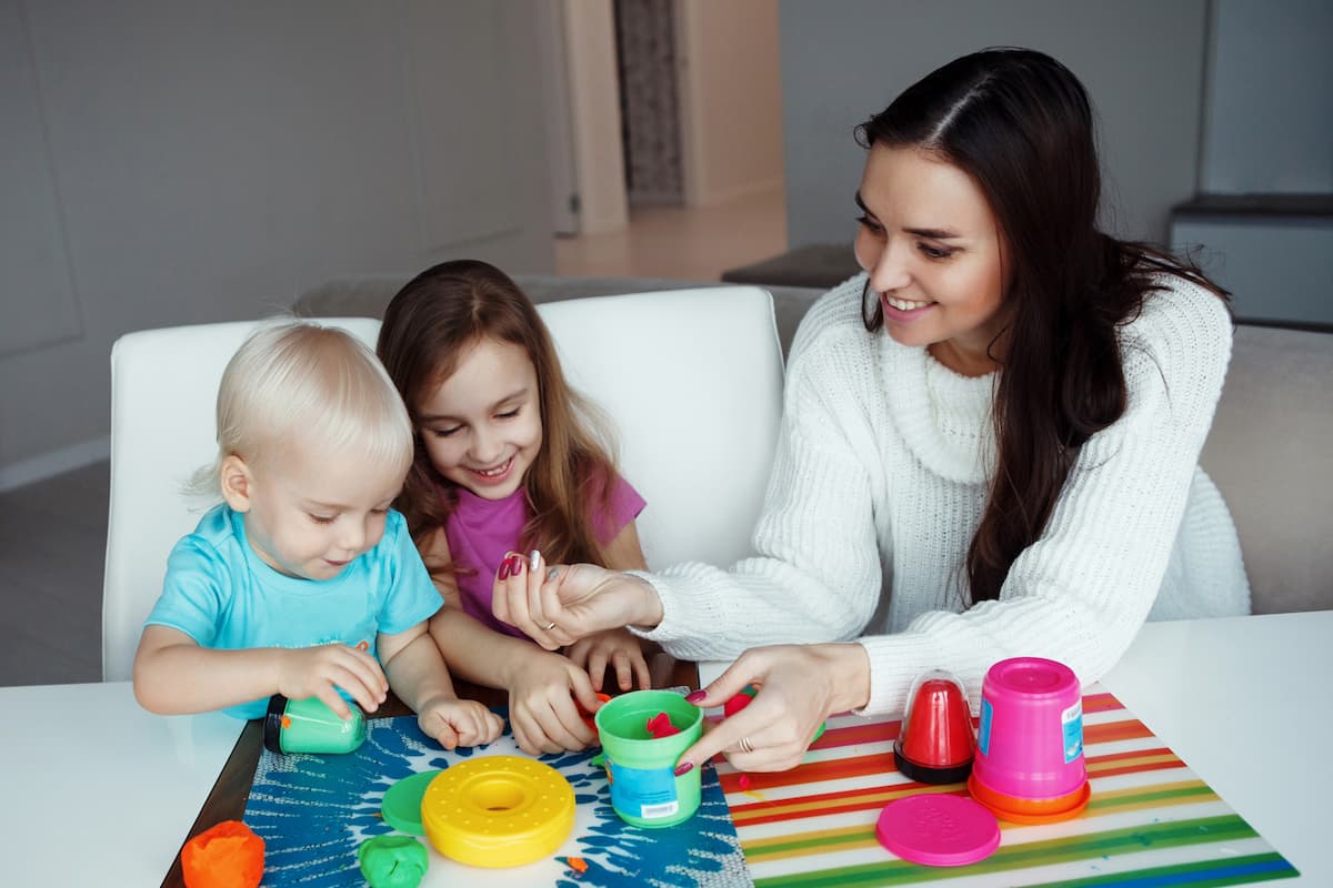 A young mother helping her children engage in play together. 