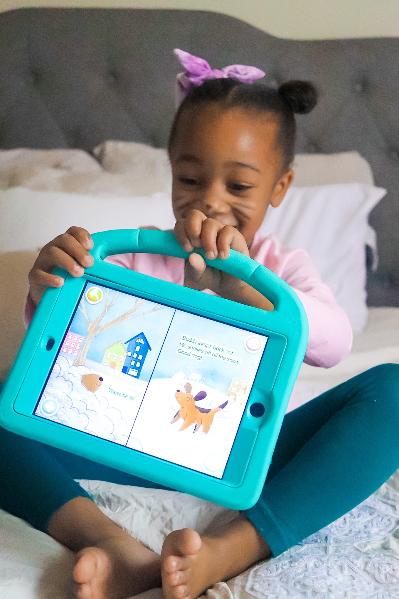 Young girl holding a light blue i-pad showing the ABCmouse story on it. 