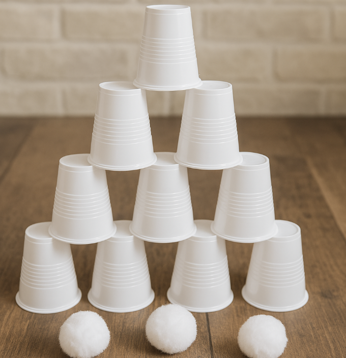 A stack of white cups with large round white pom poms sitting on a table. 
