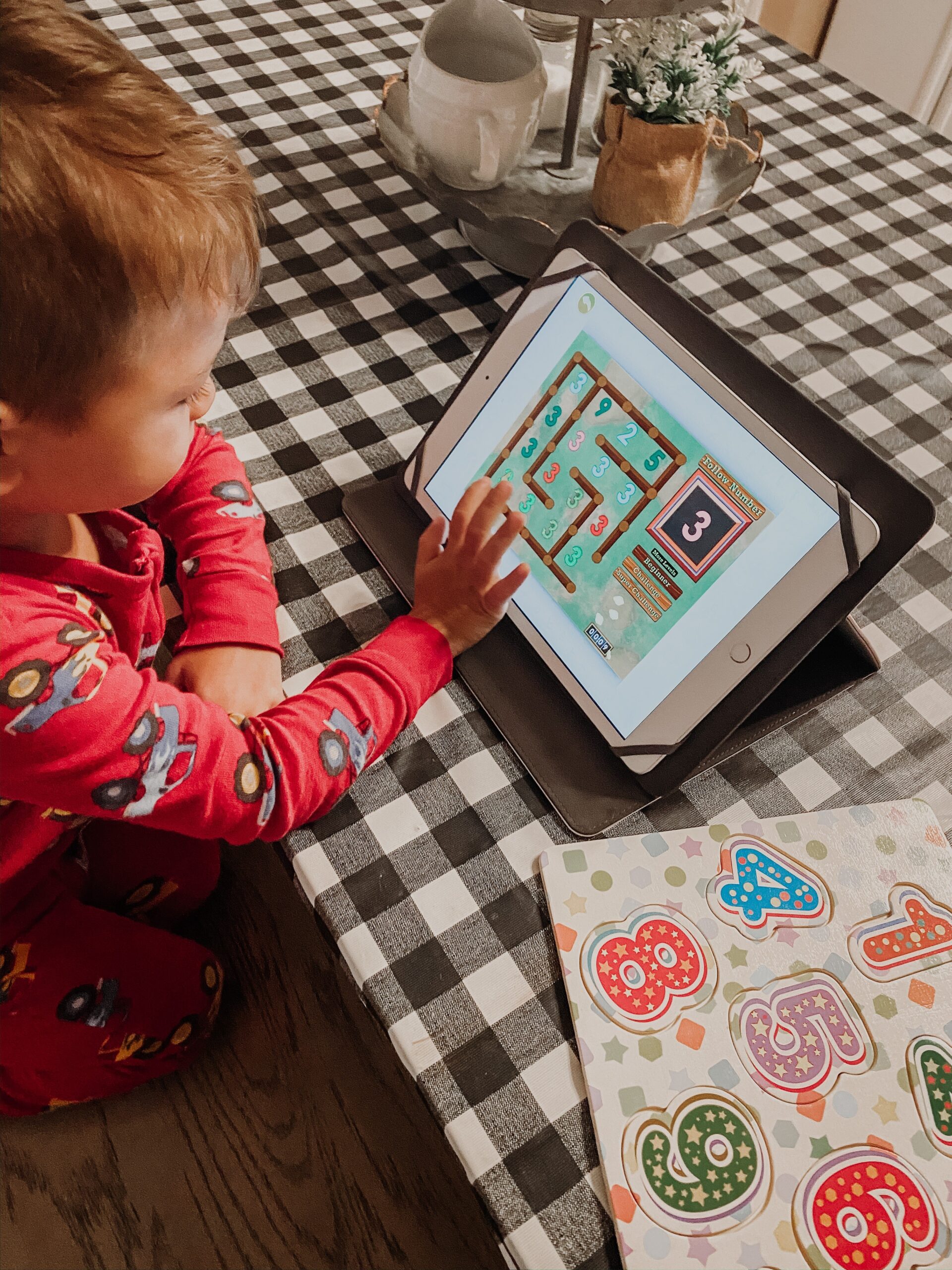 A young boy playing the ABCmouse app on a tablet sitting at a table. 