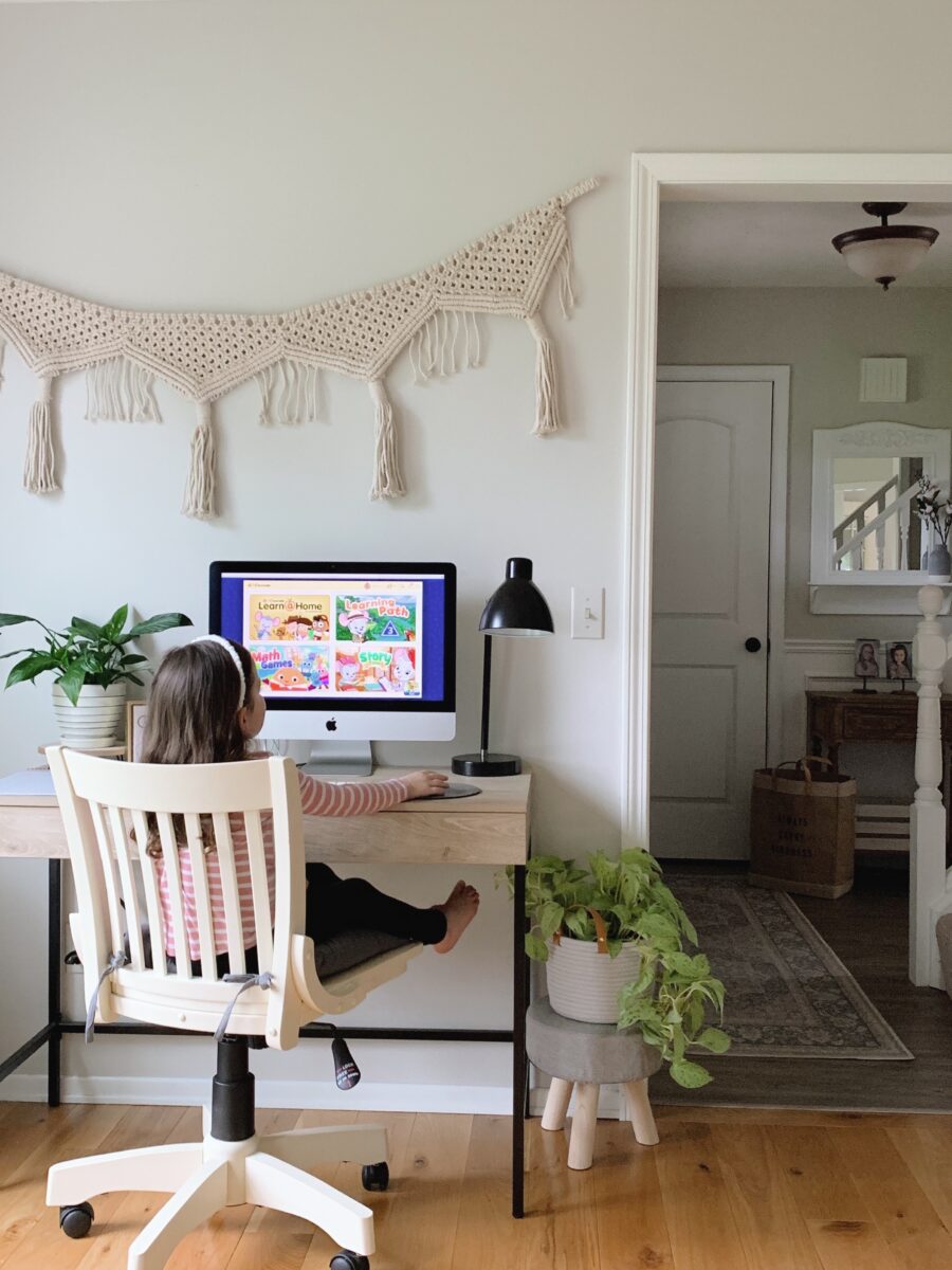 A young child sitting at a computer desk playing ABCmouse.