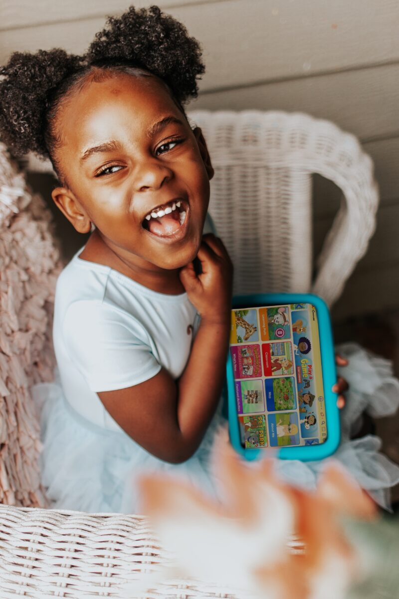 Cute young girl holding an i-pad with ABCmouse while laughing. 