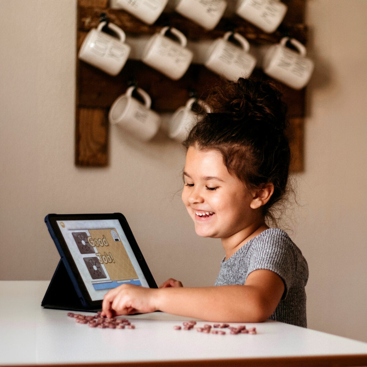 Cute little girl laughing while looking at the ABCmouse reward screen while playing the ABCmouse app on an i-pad