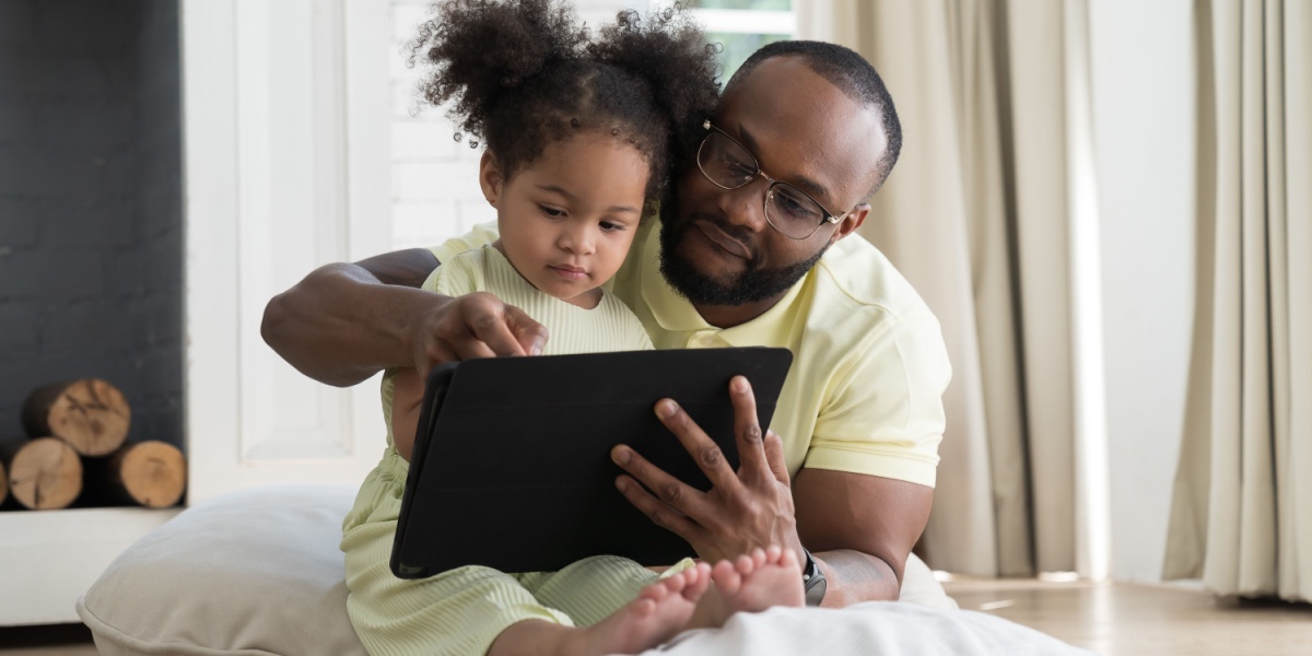 Child and parent holding a tablet playing the ABCmouse app. 