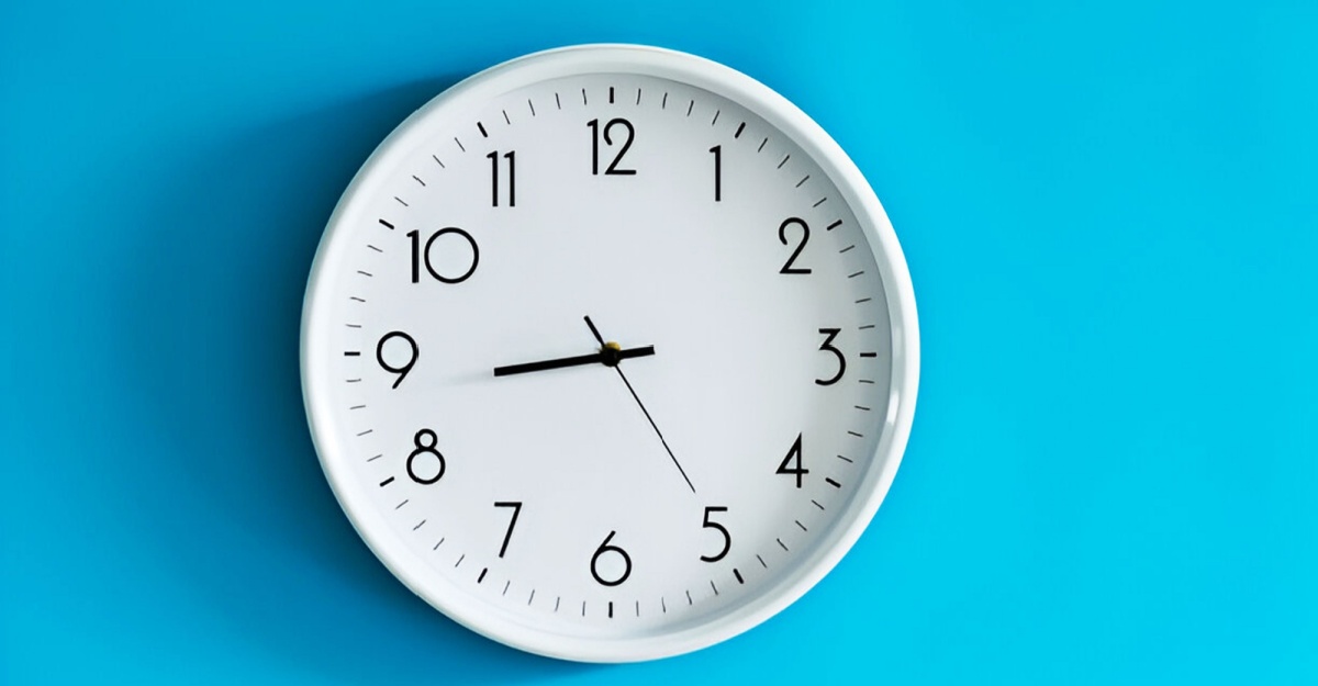 A simple clock handing on a plain light blue wall. 