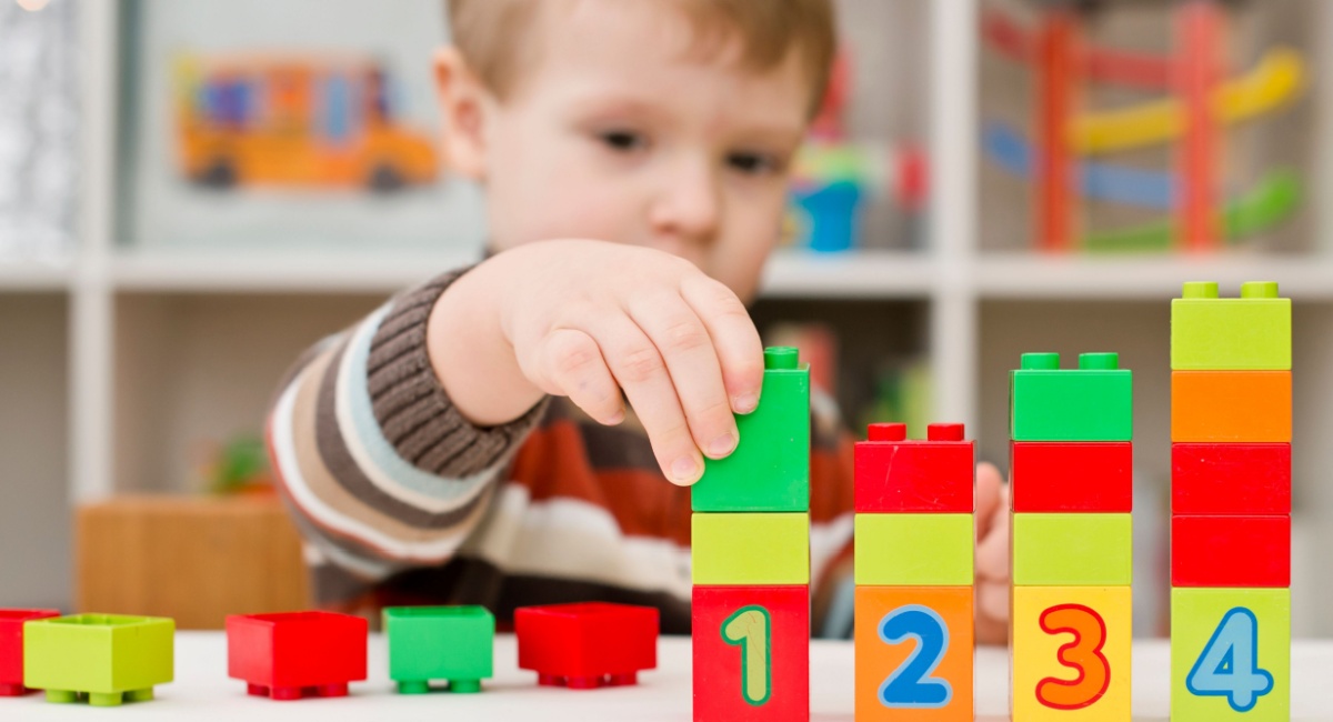 A young child building block towers with Duplo blocks in this indoor activity.