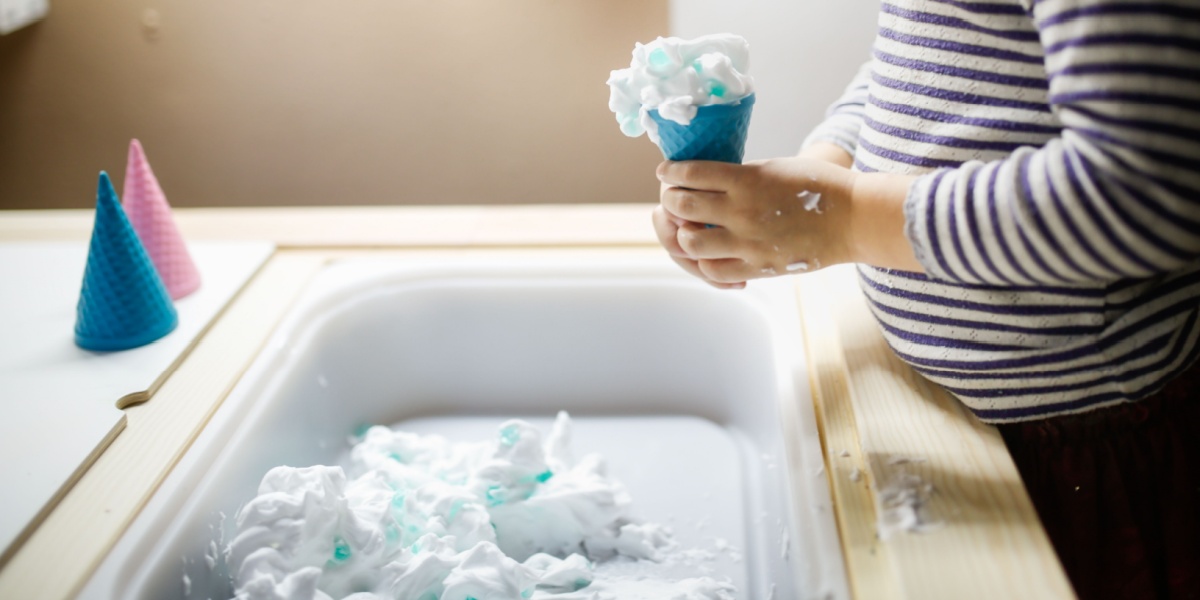 A bin filled with shaving cream and baking soda in this indoor snow activity for kids.