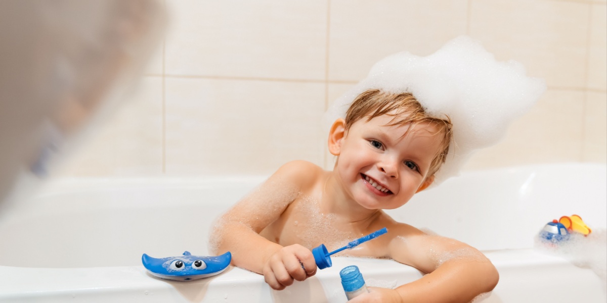 A cute little boy covered with bubbles playing in the bath.