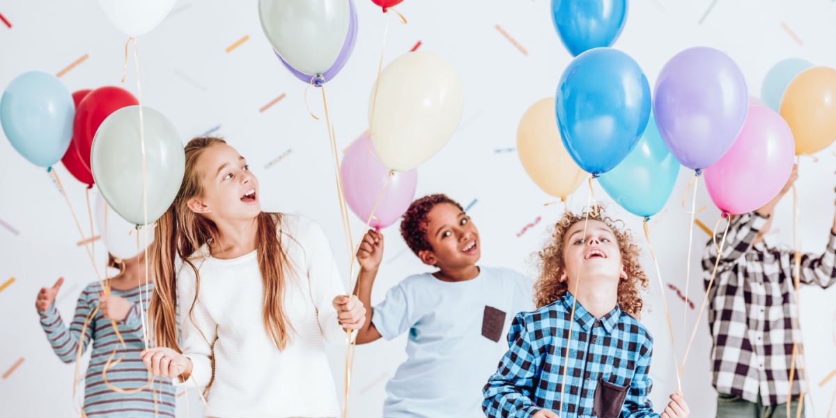 A bunch of children playing with balloons in a fun indoor dancing activity.