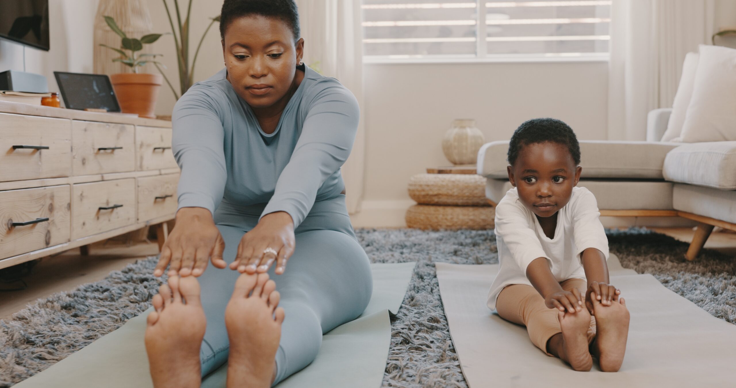 A young mother and son stretching out on yoga mats together.
