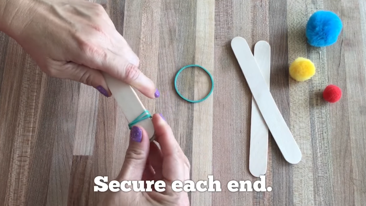 Securing both ends of stacked craft sticks with rubber bands