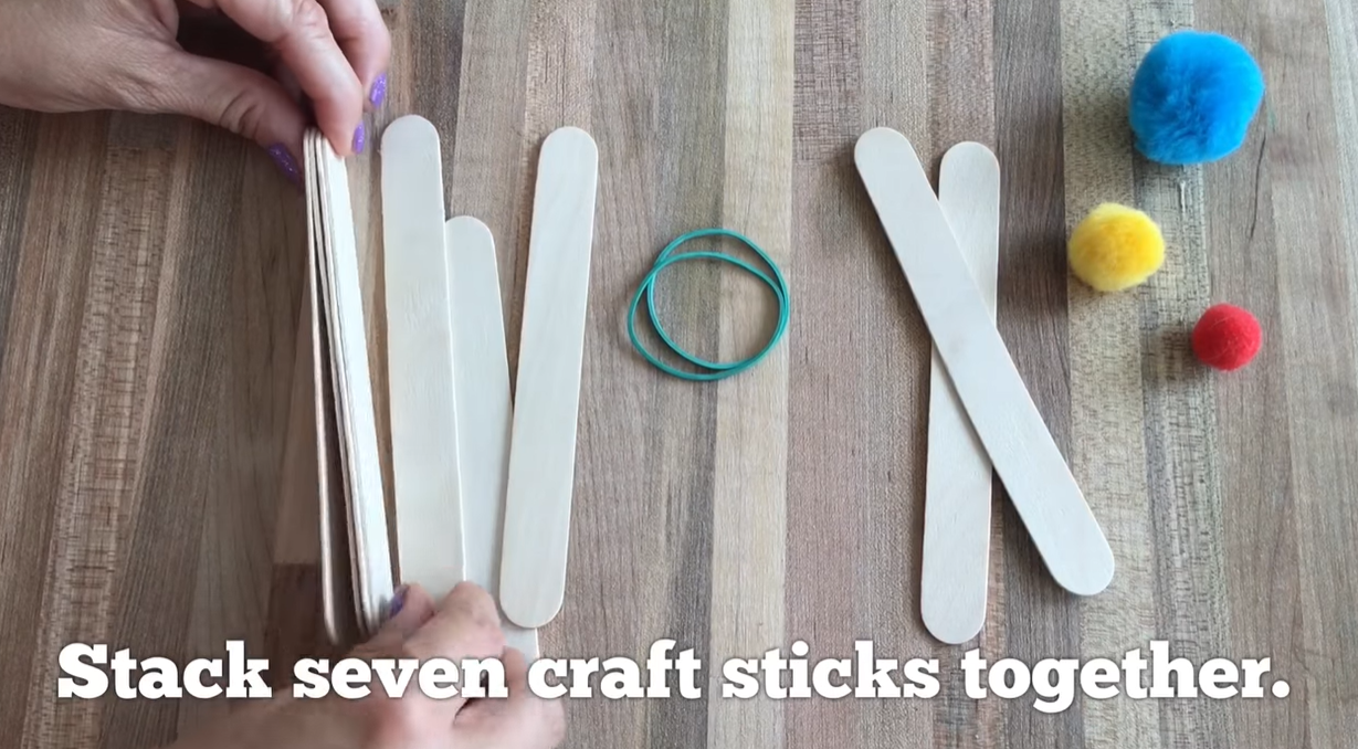 Stacking seven craft sticks together to form the base of a catapult