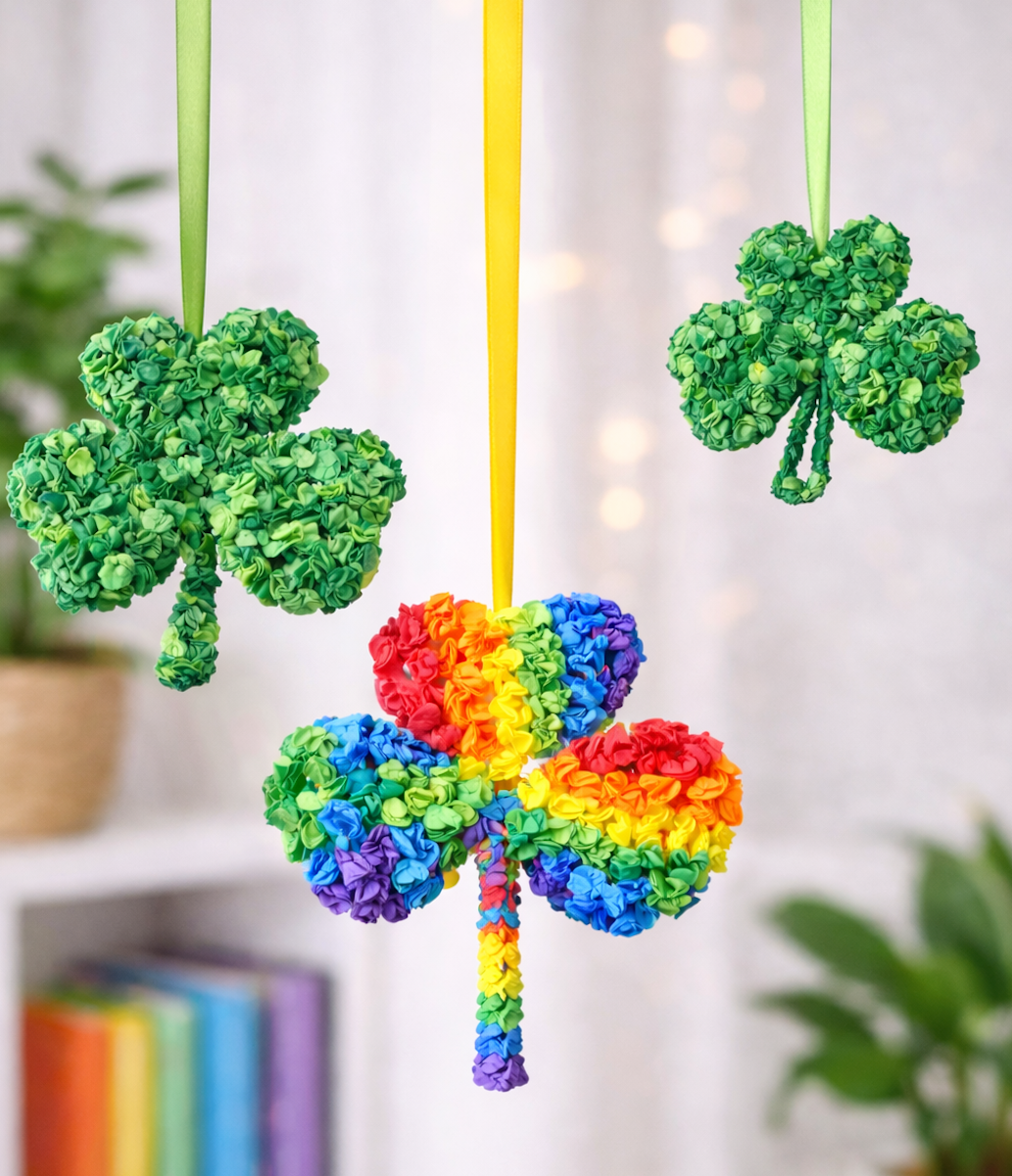 Hanging tissue paper shamrock decorations in green and rainbow colors, suspended with ribbons in a festive indoor setting.