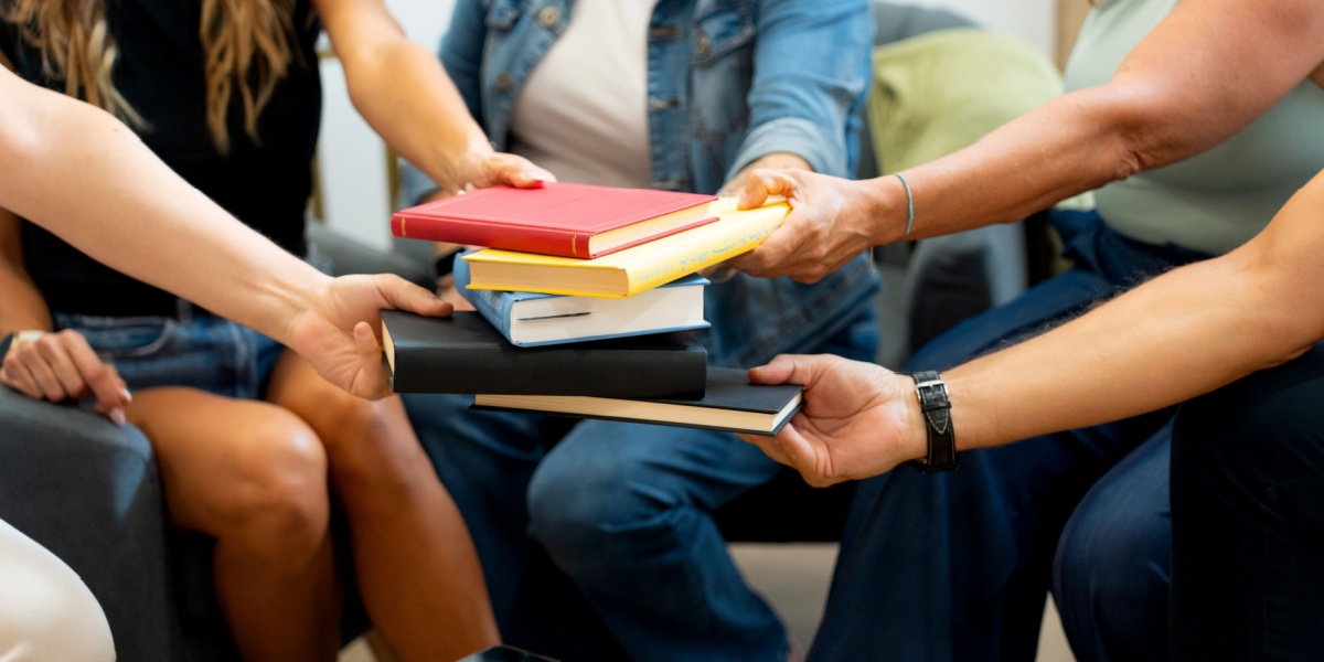 Group of people passing a stack of books to one another.