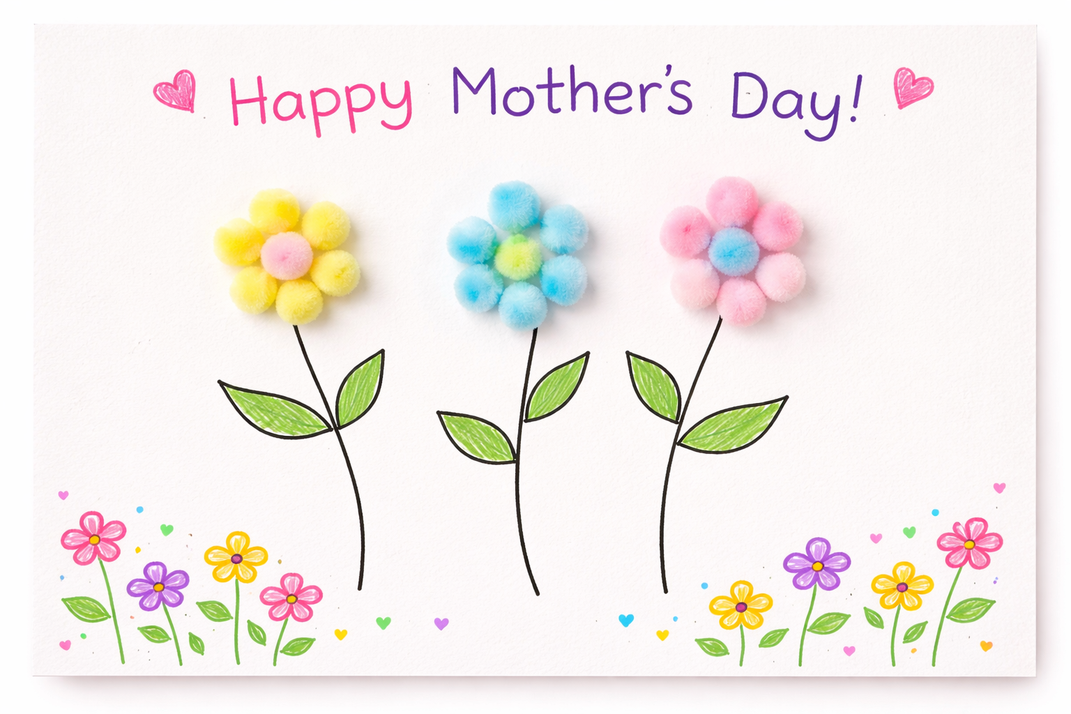 Handmade Mother’s Day card featuring three flowers made from colorful pom-poms, with drawn stems and leaves, “Happy Mother’s Day!” written at the top, and small doodled flowers and hearts along the bottom.