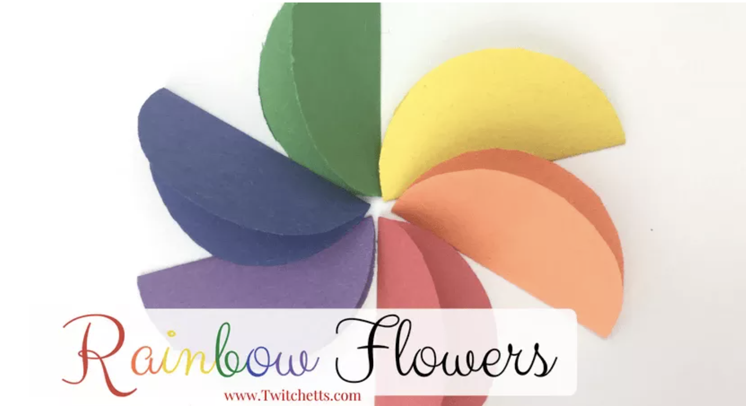 Colorful paper flower made from overlapping rainbow-colored petals arranged in a circular pattern.