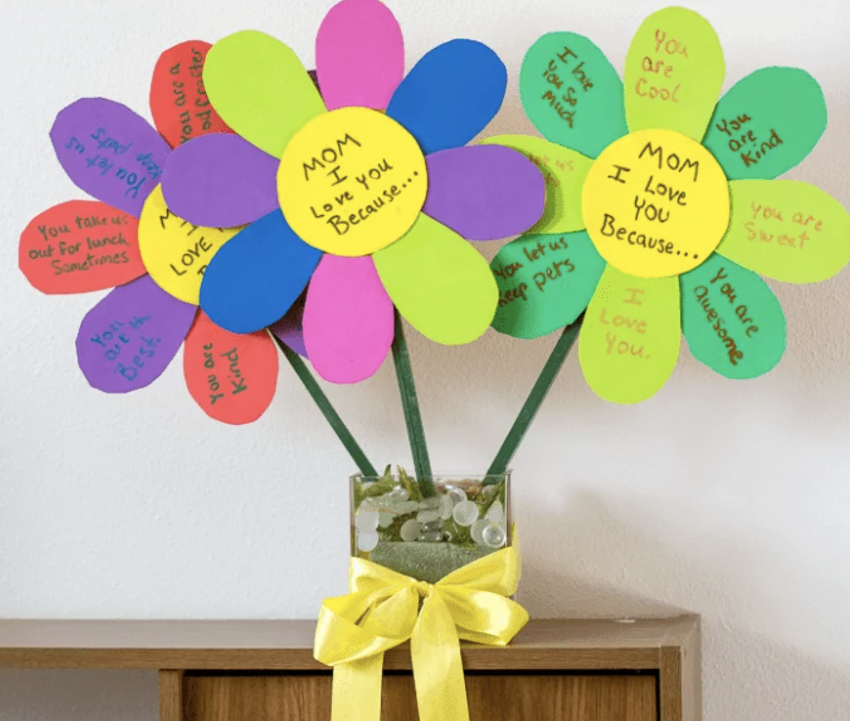Colorful paper flowers in a vase with handwritten messages on each petal for Mom.