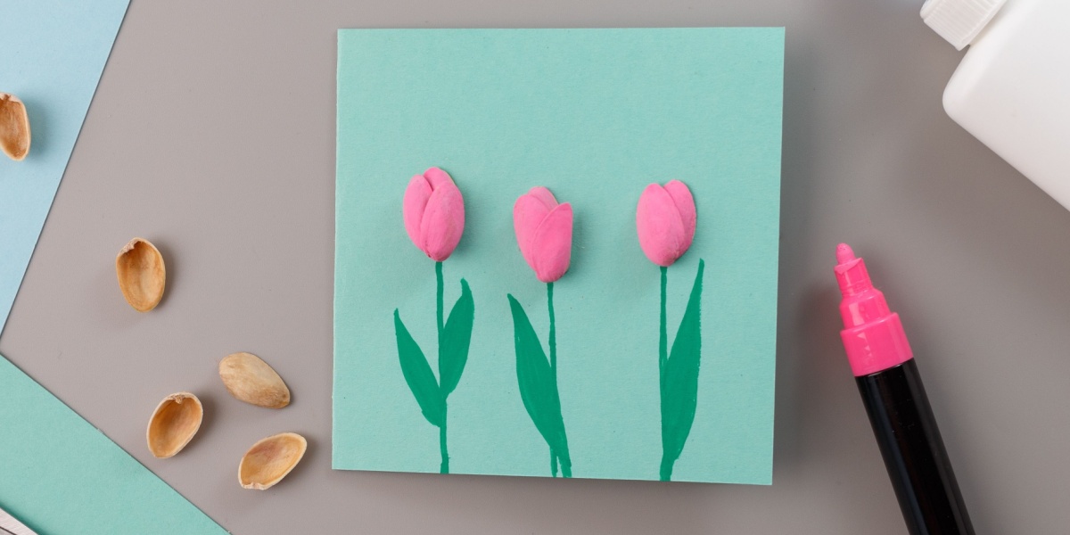 Pink pistachio shells tulip flowers on green stems against a blue background.