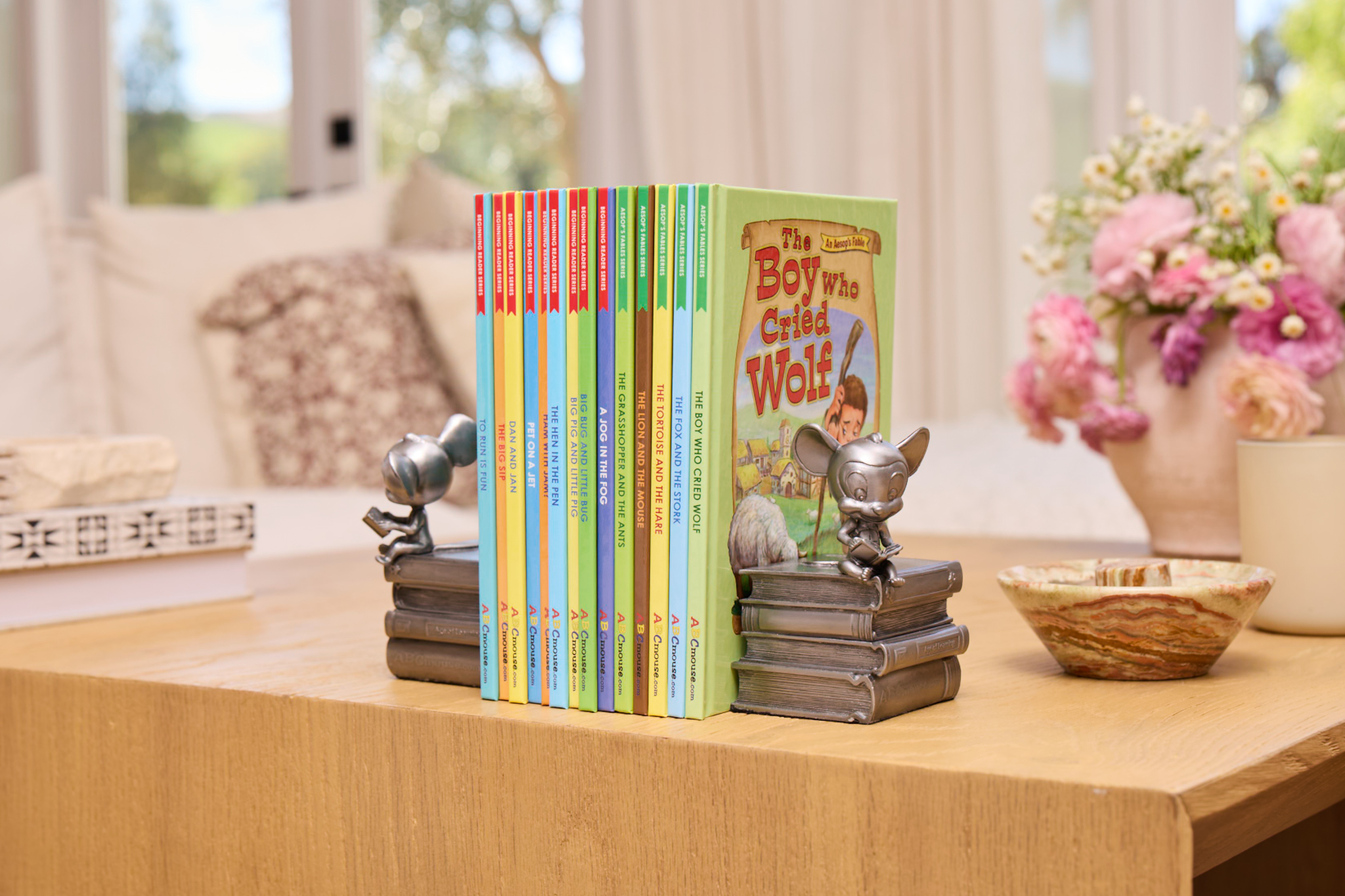 Colorful children’s book spines arranged upright on a coffee table in a bright living room.