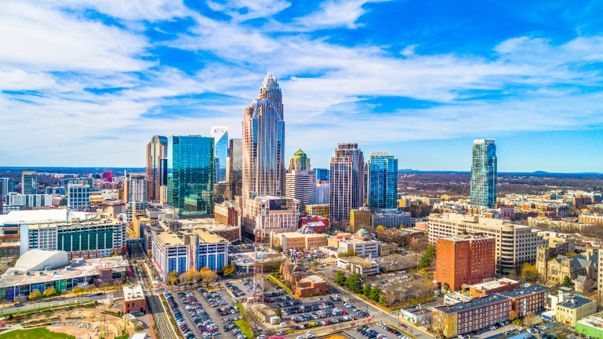 Aerial view of a downtown skyline with glass skyscrapers under a bright blue sky.